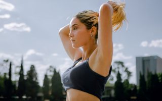 A focused woman in sportswear tying her hair, preparing for an outdoor workout in Mexico City.