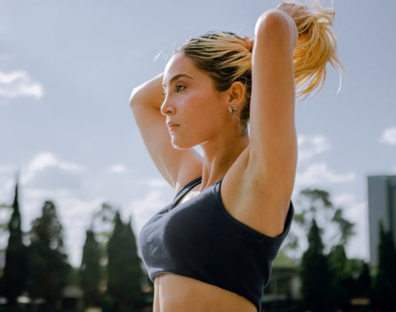 A focused woman in sportswear tying her hair, preparing for an outdoor workout in Mexico City.