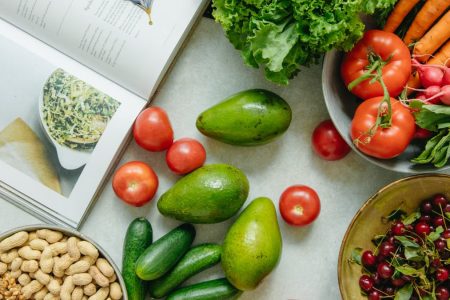 An appetizing display of fresh fruits and vegetables with a cookbook, perfect for healthy recipes.