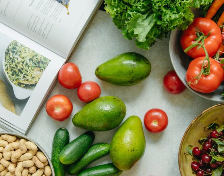 An appetizing display of fresh fruits and vegetables with a cookbook, perfect for healthy recipes.